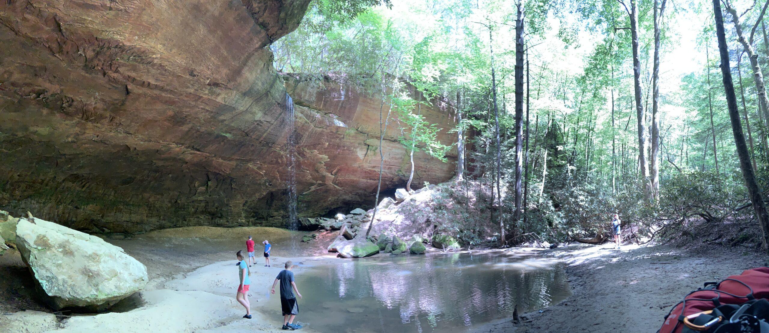Hikers at Copperas Cave in Kentucky's Red River Gorge, a unique sandstone rock shelter and popular mystery hike spot.