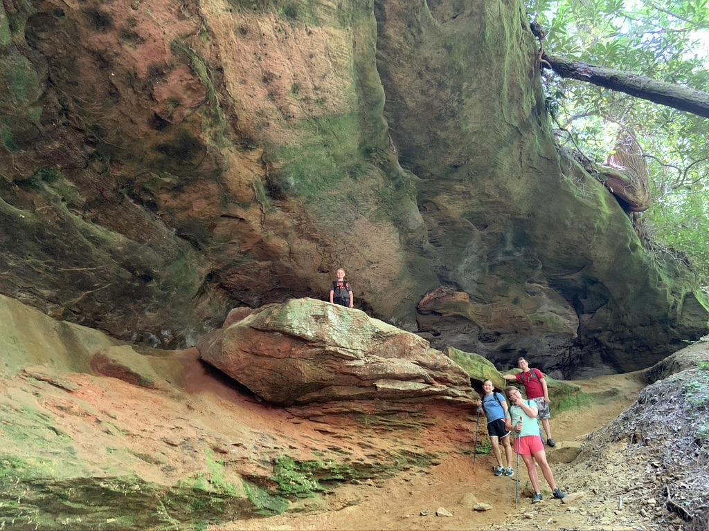 Family exploring a rock shelter at Red River Gorge, KY. Hiking adventure in Kentucky's natural beauty.