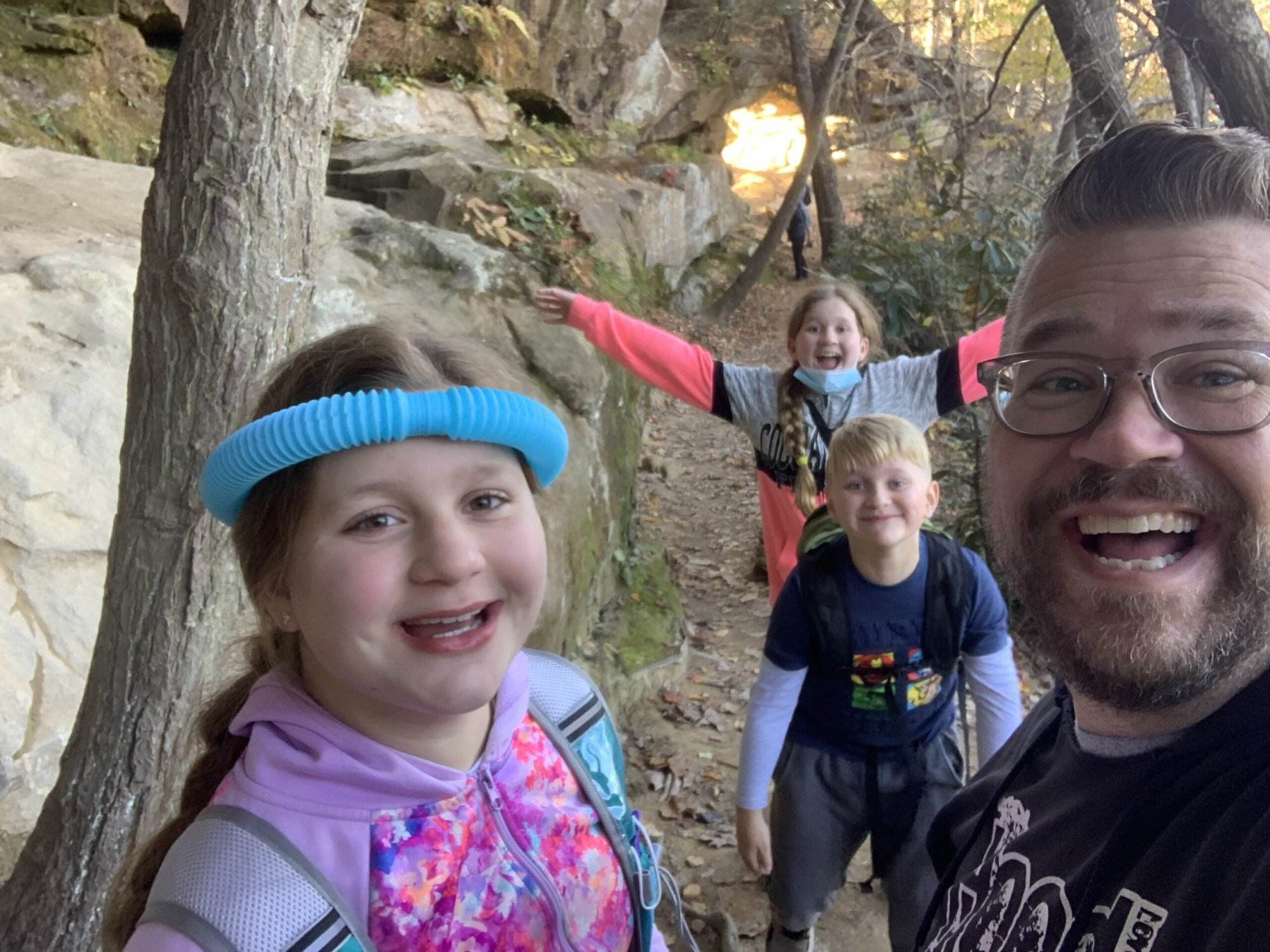 Family selfie hiking in Red River Gorge, KY, near a rock shelter. Fun outdoor adventure!